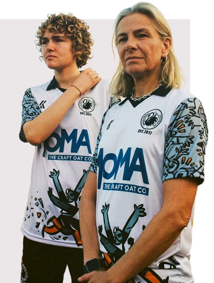 Two sportswomen model OLIK Sports kits. The shirts have a white body and blue sponsors logo and light blue sleeves with patterns on. The shirt has a black 70s-style collar.
